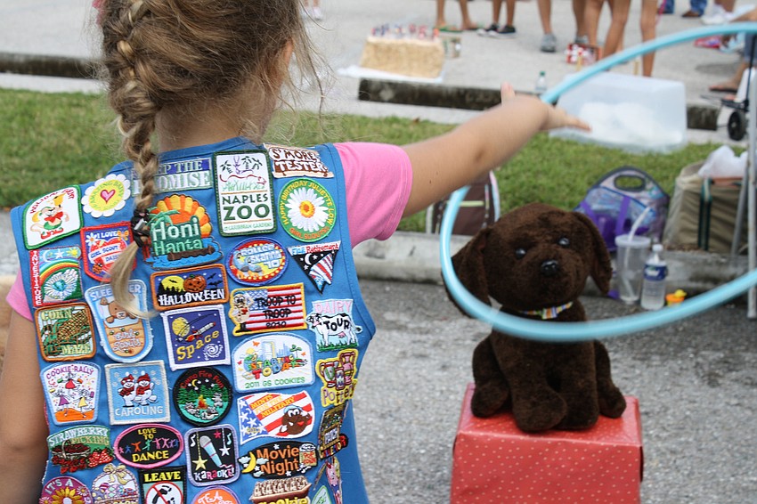 Six-year-old Faith Chaney throws a hula-hoop around a bear.  Faith has been a Girl Scout for two years and her favorite cookie is the Thin Mint.