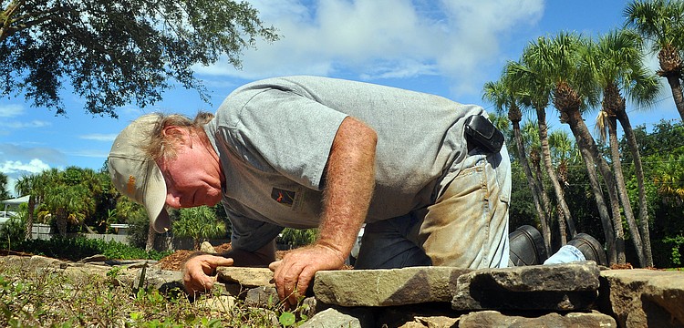 Tyrone Edwards, of Wilhem Bros., works on putting together a rock retaining wall out in front of St. Michael the Archangel Catholic Church. "It's kind of like a puzzle," said Edwards of his work.