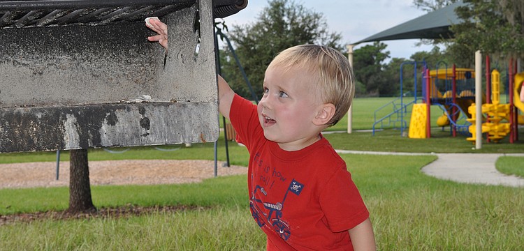 Eighteen-month-old Brayden Ridenour enjoyed tossing shells onto the grill while playing at Adventure Park in Greenbrook this morning.