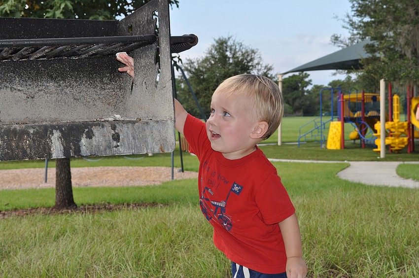 Eighteen-month-old Brayden Ridenour enjoyed tossing shells onto the grill while playing at Adventure Park in Greenbrook this morning.