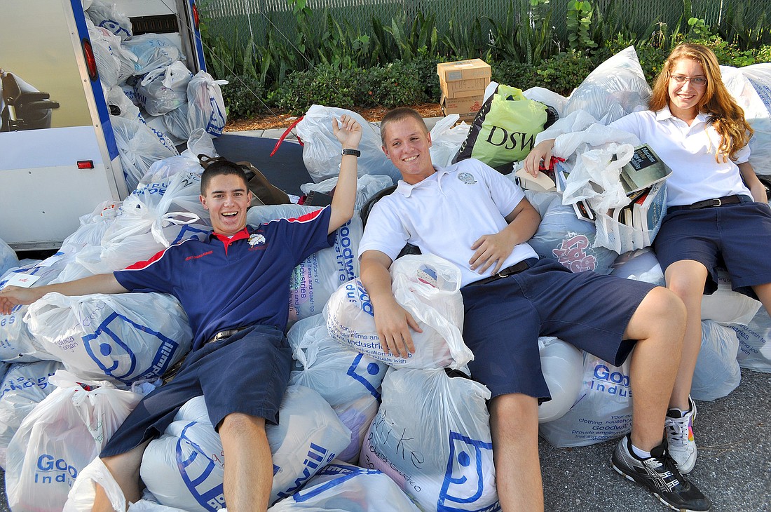Mac Charalambous, Beau Arnold and Claudia Scheb lounge on the garbage bags full of donated items.