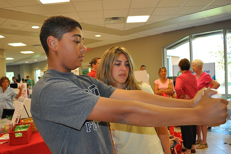 Jill Rose, right, helps 15-year-old Cameron Darby get his body fat measured.