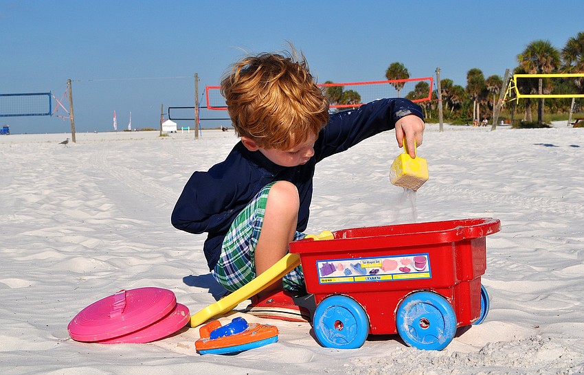 Patrick Fleming, 4, enjoys pouring sand in his little red wagon. Fleming is on vacation from Massachusetts along with his mother and father.
