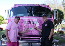 Danny Baughman and Dave Graybill pose in front of "Debbie," at pink firetruck covered in signatures. Each truck is usually named for a woman who has had cancer and had an impact on the community. "Debbie" is Baughman's mother-in-law.