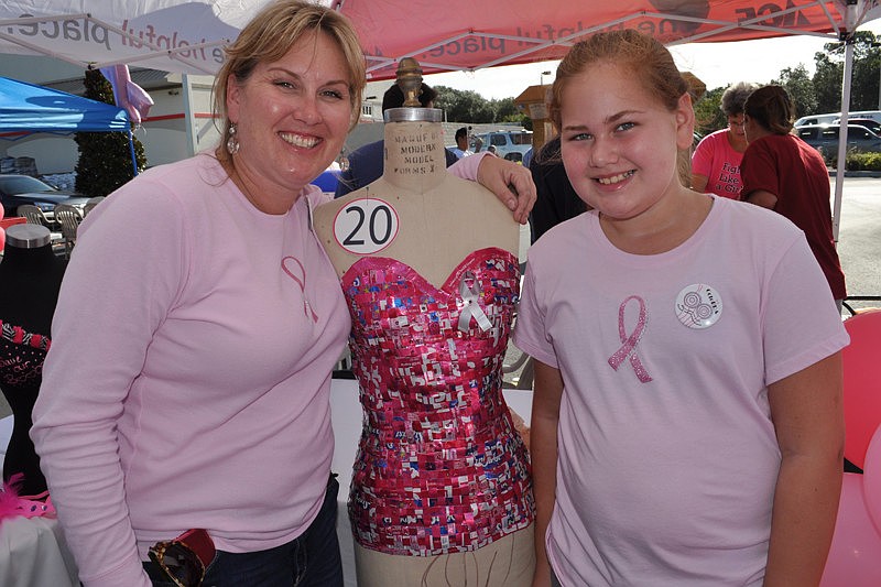Summerfield resident Michelle Clinton, with her daughter, Ava, stands next to the bra she made out of recycled Tab and strawberry Sunkist.