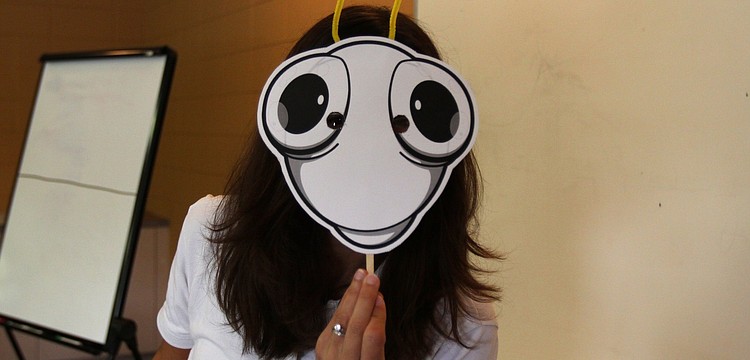 Jennifer Holt hides behind a blank, bug face that the preschoolers at St. Boniface got to decorate.