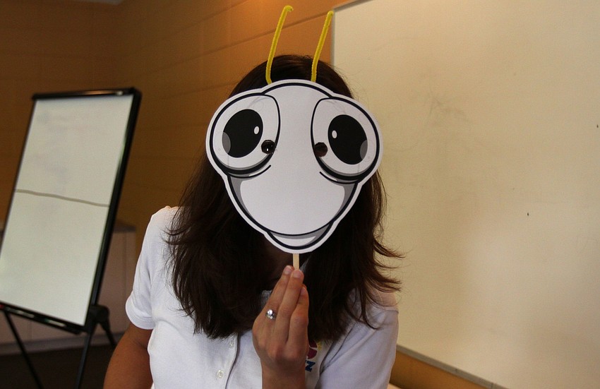 Jennifer Holt hides behind a blank, bug face that the preschoolers at St. Boniface got to decorate.