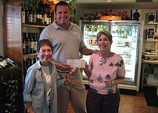 Susan Landau and Madelyn Spoll of the Garden Club get presented a check from Hal Christensen with Harry's Continental Kitchens for the wine tasting fundraiser.