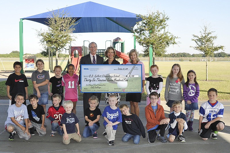 Pat and Charlene Neal, of Neal Communities, present Gullett Principal Kathy Hayes and students with a check.