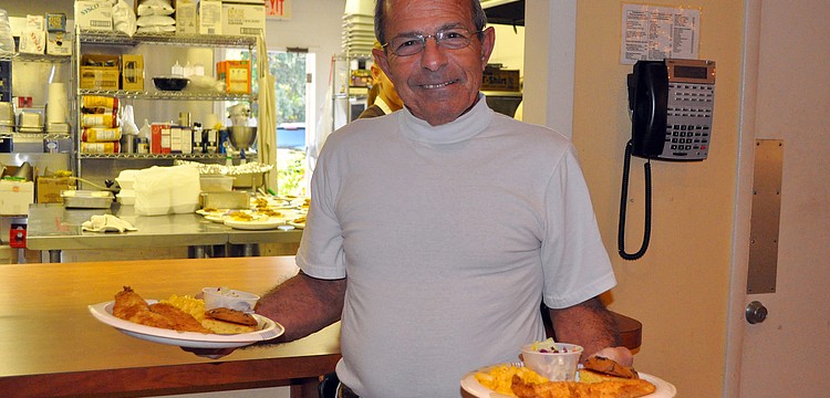Gary Porretta picks up two plates, one for himself and one for his wife, Mary, Friday, Nov. 4, during the fish fry at St. Boniface.