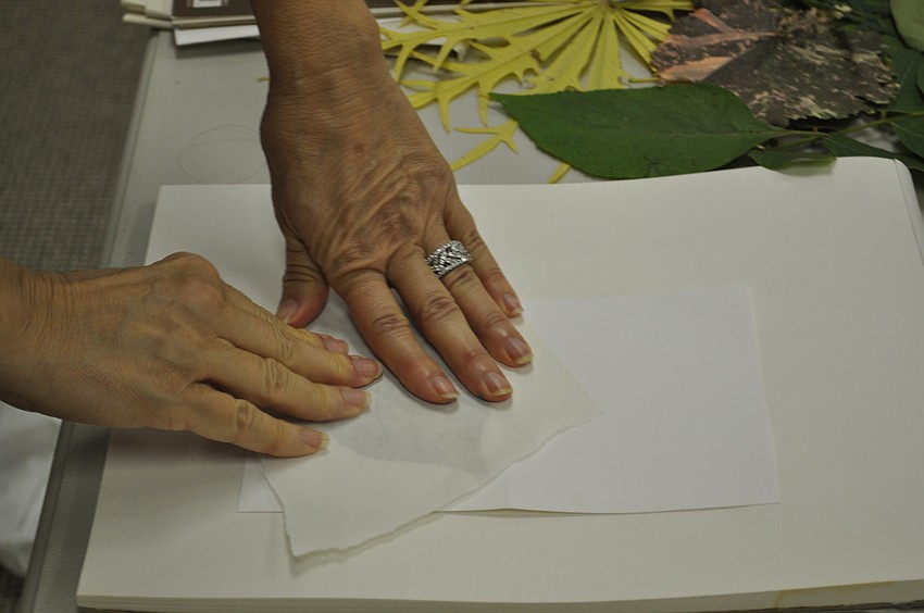 Migliore presses firmly onto the leaf covered in pigment to transfer the leafs image onto the note card