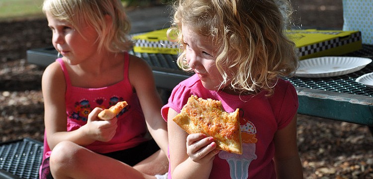Ella Carson, behind, and Isabelle McKeon, front, feasted on pizza while watching other children play basketball.