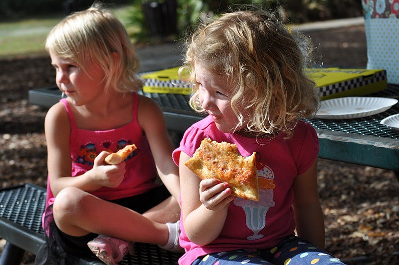 Ella Carson, behind, and Isabelle McKeon, front, feasted on pizza while watching other children play basketball.