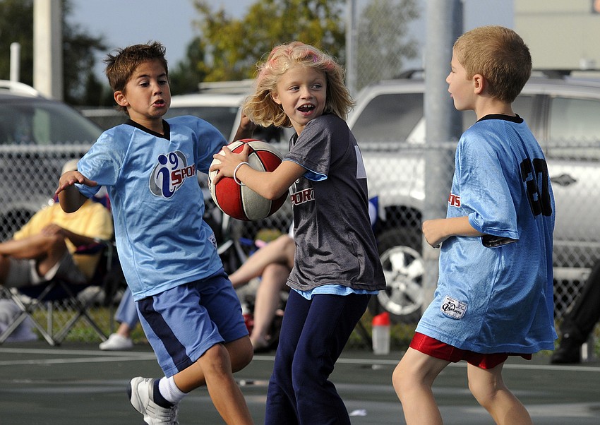 Eight-year-old Jason Jessup, left, and James Crain, 7, race to double-team Kayla Cummings, 8.