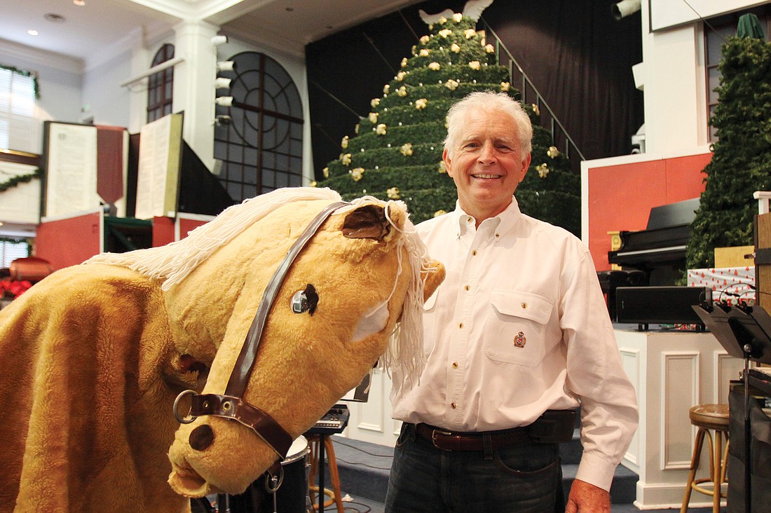 Dan Cracchiola poses with Levoie Hipps, dressed in his horse costume, in front of the Christmas tree.