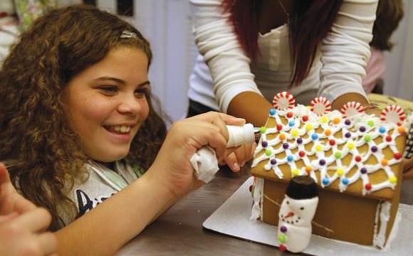 Mya Carter frosts the front of the Girls Inc. gingerbread house. Photo by Rachel S. O'Hara.