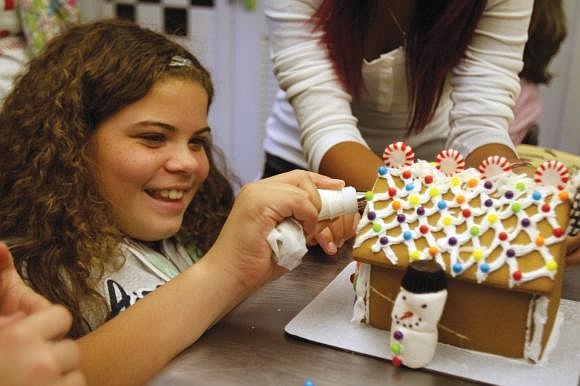 Mya Carter frosts the front of the Girls Inc. gingerbread house. Photo by Rachel S. O'Hara.