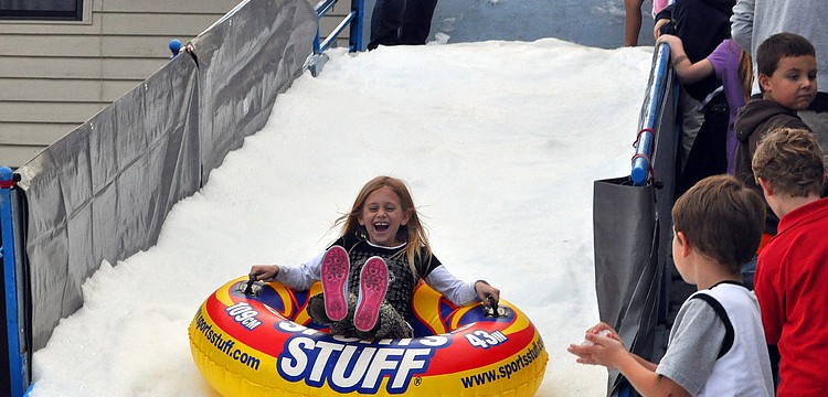 Kids in line watch Blythe Snyder, 7, scream with delight as she flies down the Snow Slide, Friday, November 9, during Southside Stroll.