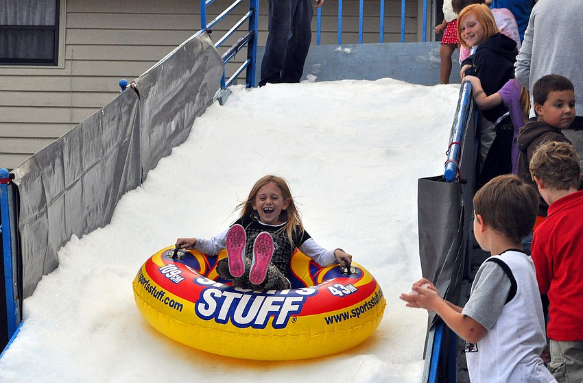 Kids in line watch Blythe Snyder, 7, scream with delight as she flies down the Snow Slide, Friday, November 9, during Southside Stroll.