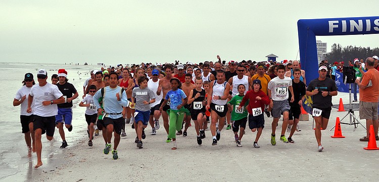 The runners for the 5K start off running down the beach, Saturday, Dec. 10, for the 35th annual Sandy Claws run on Siesta Key Beach.