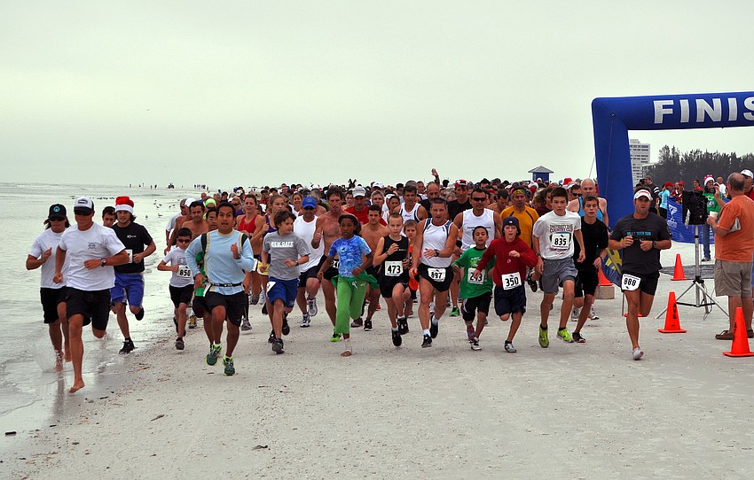 The runners for the 5K start off running down the beach, Saturday, Dec. 10, for the 35th annual Sandy Claws run on Siesta Key Beach.