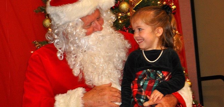 Nevaeh Most, 2, smiles big while talking with Santa, Tuesday, Dec. 13, during Healthy Families Sarasotaâ€™s Holiday Party inside FirstBaptist Sarasotaâ€™s Family Life Center.