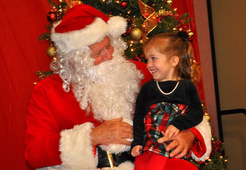 Nevaeh Most, 2, smiles big while talking with Santa, Tuesday, Dec. 13, during Healthy Families Sarasotaâ€™s Holiday Party inside FirstBaptist Sarasotaâ€™s Family Life Center.