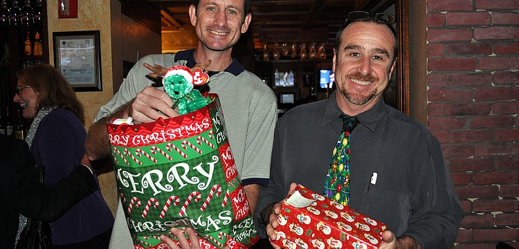 Alan Misch and Tom Darby hold up the presents they brought to the DSA holiday party.