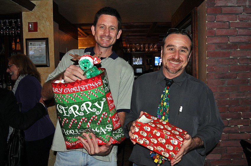 Alan Misch and Tom Darby hold up the presents they brought to the DSA holiday party.