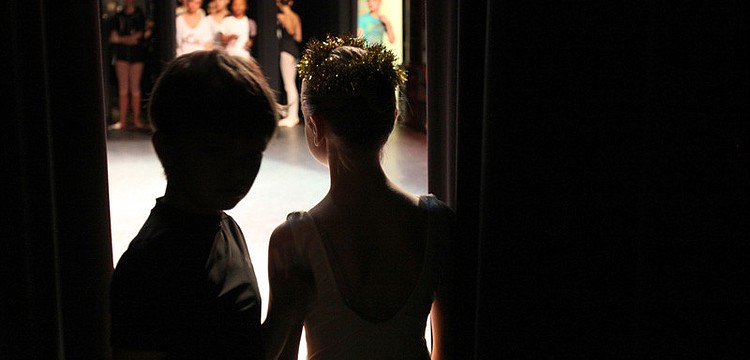 Two 8-year-olds wait in the wings before a spacing rehearsal for the finale.
