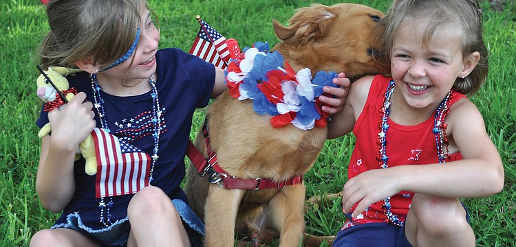 Noelle and Heather Amorini play with their dog, Tucker, in July at the Longboat Key Freedom Fest celebration.