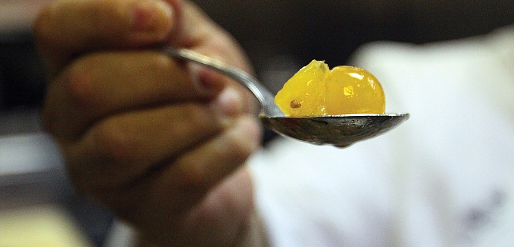 Longboat Key Club Chef de cuisine Aaron Chavaria holds up a spoonful of citrus tomato confit, while preparing for dinner service in August at Sands Pointe restaurant.