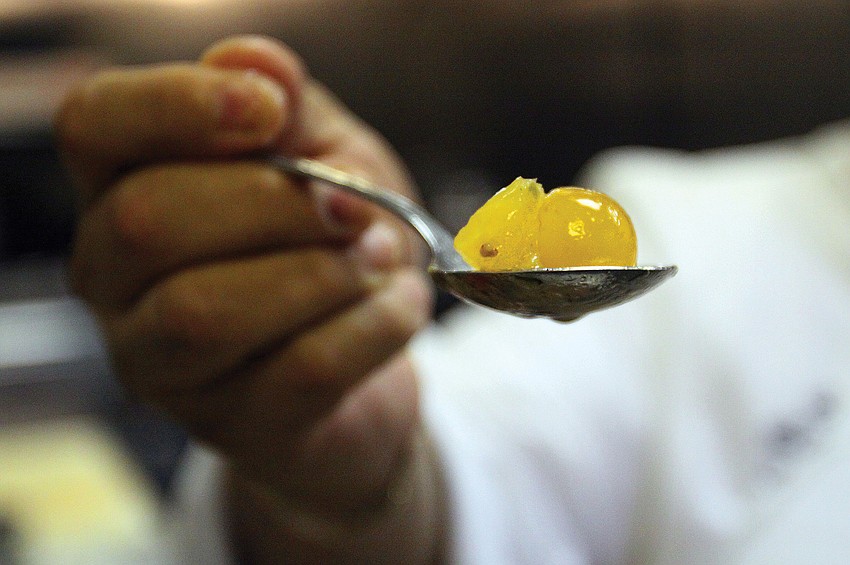 Longboat Key Club Chef de cuisine Aaron Chavaria holds up a spoonful of citrus tomato confit, while preparing for dinner service in August at Sands Pointe restaurant.