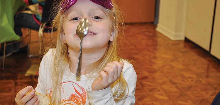 Riley Putnam practices her spoon-sticking ability in January at a Church of the Redeemer dinner.