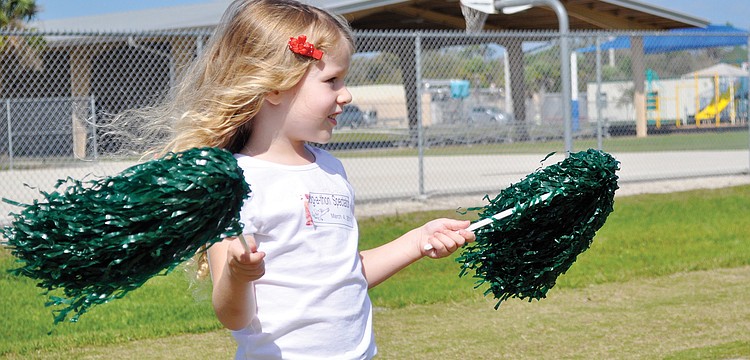 Cameron Seguin cheers on her big sister by waving pom-poms in the air at Tatum Ridge Elementaryâ€™s March jog-a-thon.