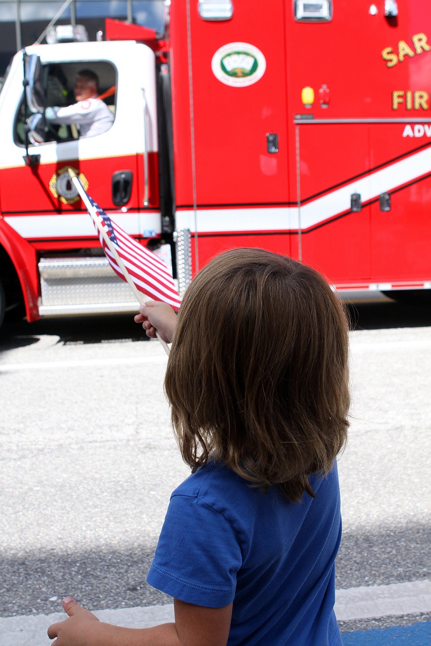 Brittin Sullivan, 4, waves his flag at one of the fire trucks that went by Sunday, Sept. 11, during the Remembrance March.