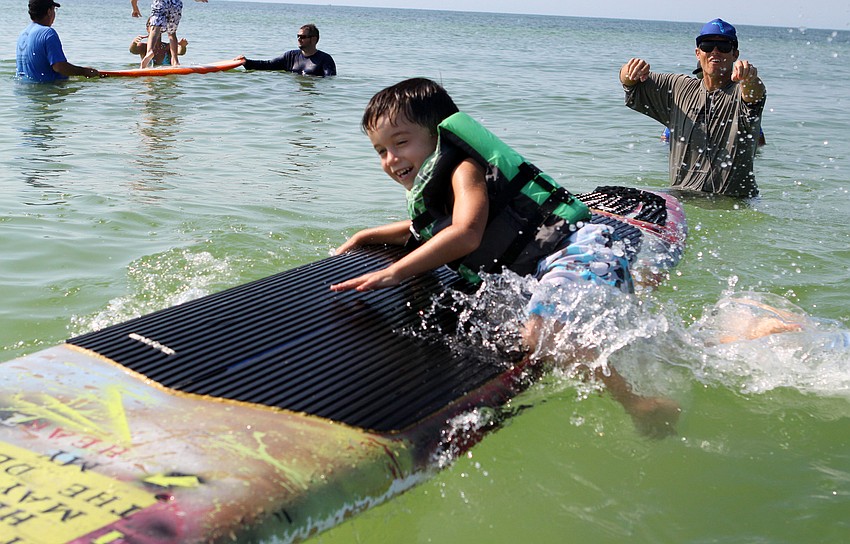 Isaiah Mendoza, 5, takes his ride sideways after given a push by his surf guide Jacob Shields.