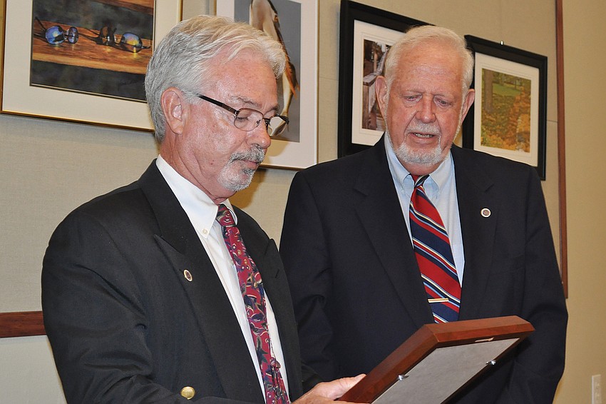Incoming Mayor Jim Brown received a plaque from outgoing Mayor George Spoll at a March Town Commission meeting.
