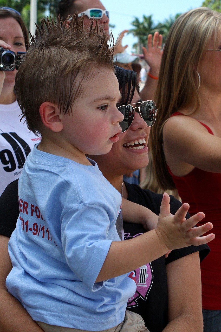 Melina Adkins holds Brandon Aitken, 2, as they cheer for the firefighters who marched Sunday, Sept. 11, in the Remembrance March.