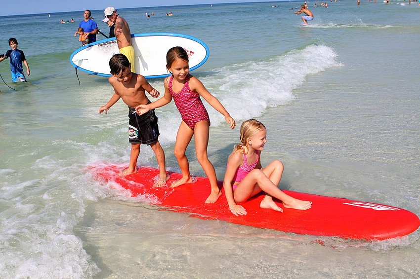Christian Ordetx, 6, Sophia Columbo, 6, and Olivia Heath, 6, all ride in together on one board Saturday, Sept. 17, at the Siesta Key Public Beach.