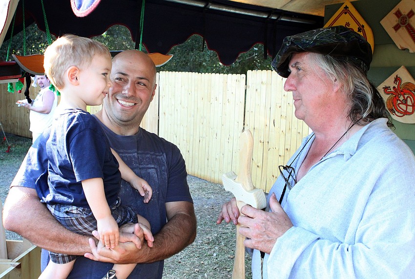 Rafael Wasserman, 2, and Gabriel Wasserman talk to Rick Marose, the owner of the Black Swan Company that makes wooden swords and shields.