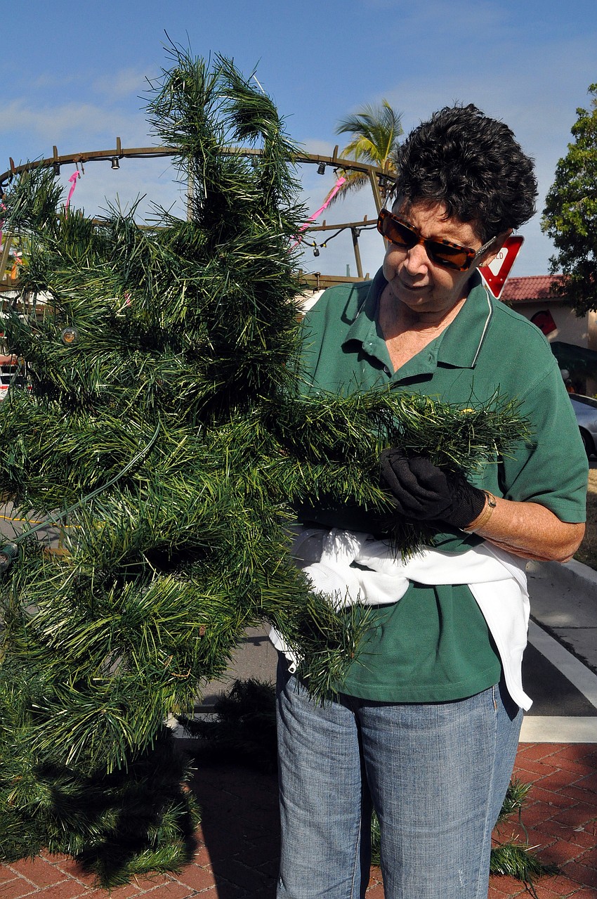 Mary Whittington tries to â€œfluffâ€ up a tree branch before putting it onto the tree. By helping out, Whittington says that it makes her feel like the tree is also her tree because she can say she helped to put it together.