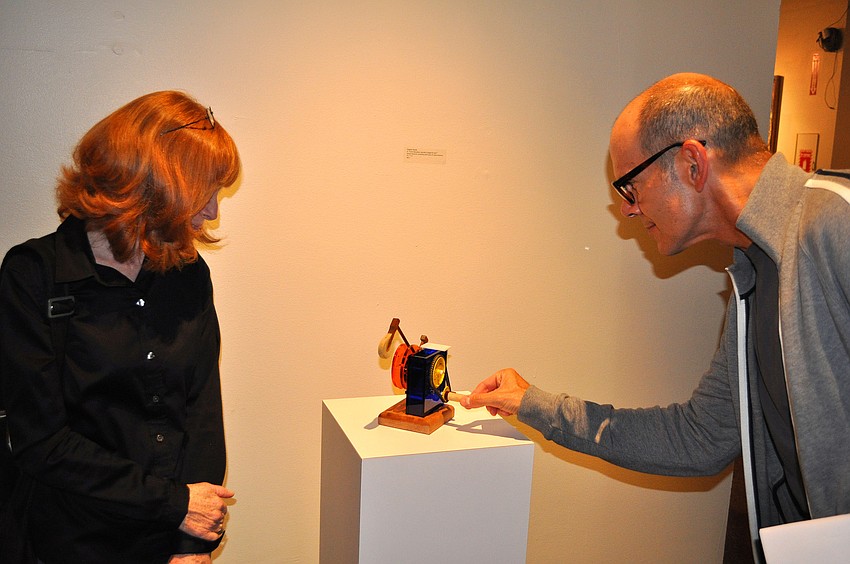 John Pirman plays with one of Steven Strenkâ€™s pieces as Janet Minker looks on during the opening of THIRTEEN, Friday, Dec. 9, at G Wiz.