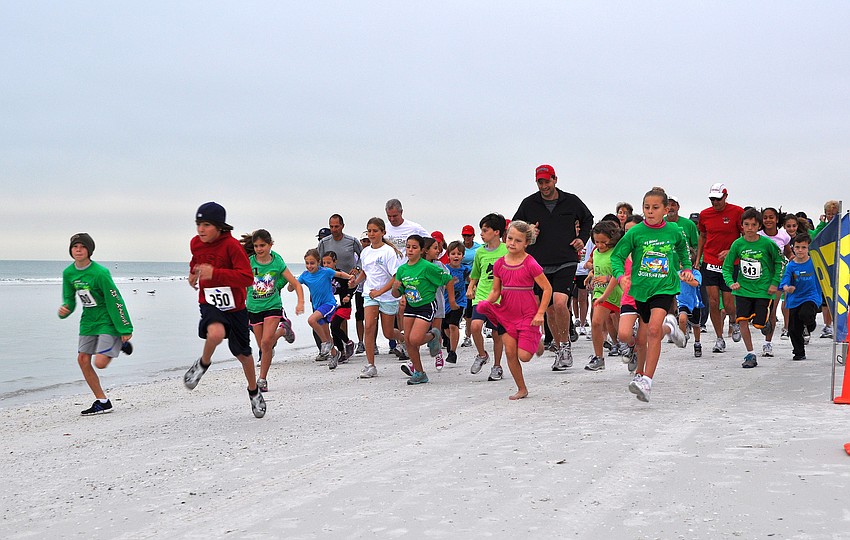 Those who participated in the 1-mile fun run associated with the Sandy Claws event begin running down the beach.