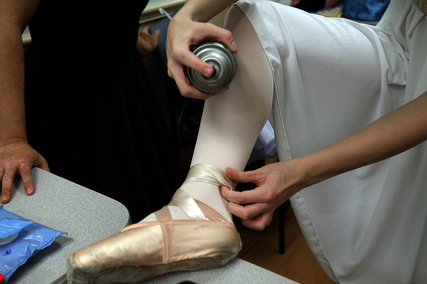 A dancer sprays hairspray on her ribbons to keep them from popping out on stage.