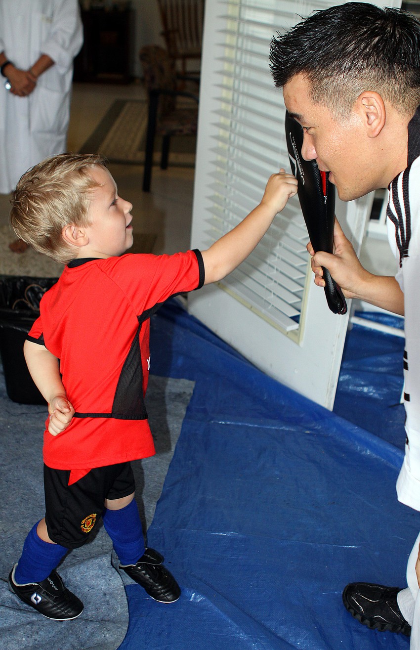 Sawyer Sobeleski punches the punching pad held by Master Hwang.