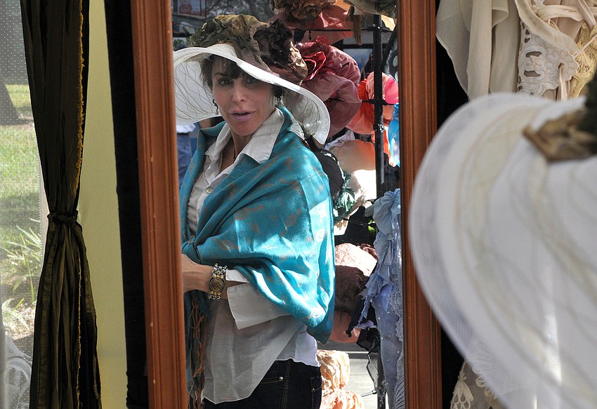 Lauren Walsh tries on a hat inside Kathryn Page's booth, Sunday, Nov. 13, during the 23rd Annual St. Armands Art Festival.