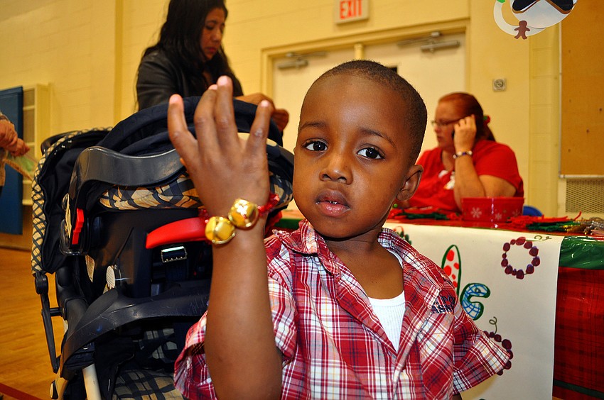 Jaylon Williams, 2, shows off the jingle bell bracelet that was made for him at one of the craft tables