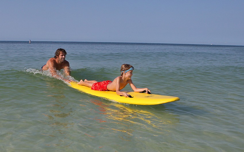 Dave Scott gives Julian Repetto, 7, a push Saturday, Sept. 17, during the Hang Ten for Autism surf event at the Siesta Key Public Beach.
