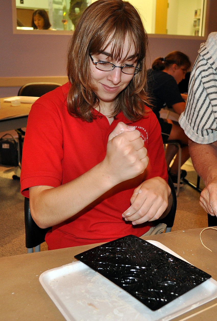 Sam Sera, 12, pounds the background pattern onto her piece of clay.